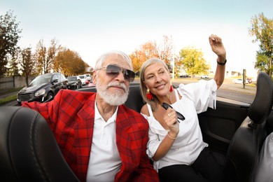 Photo of Senior couple enjoying cabriolet ride in city, wide angle lens