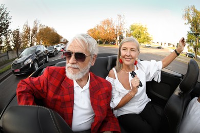 Photo of Senior couple enjoying cabriolet ride in city, wide angle lens