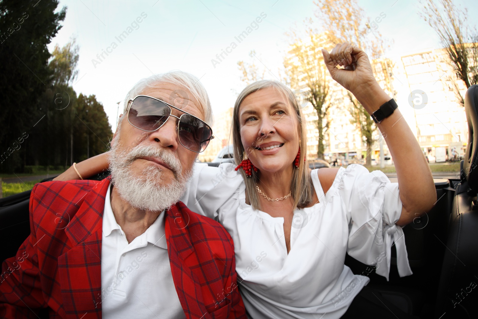 Photo of Senior couple enjoying cabriolet ride in city, wide angle lens