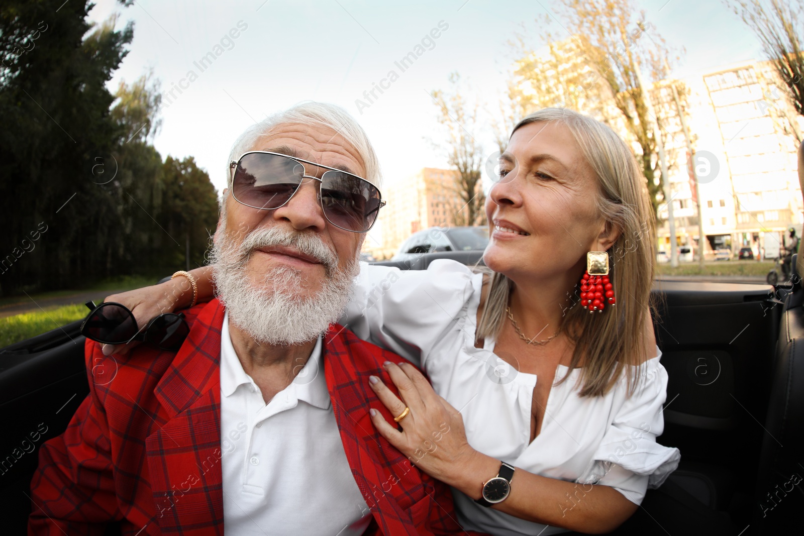 Photo of Senior couple enjoying cabriolet ride in city, wide angle lens
