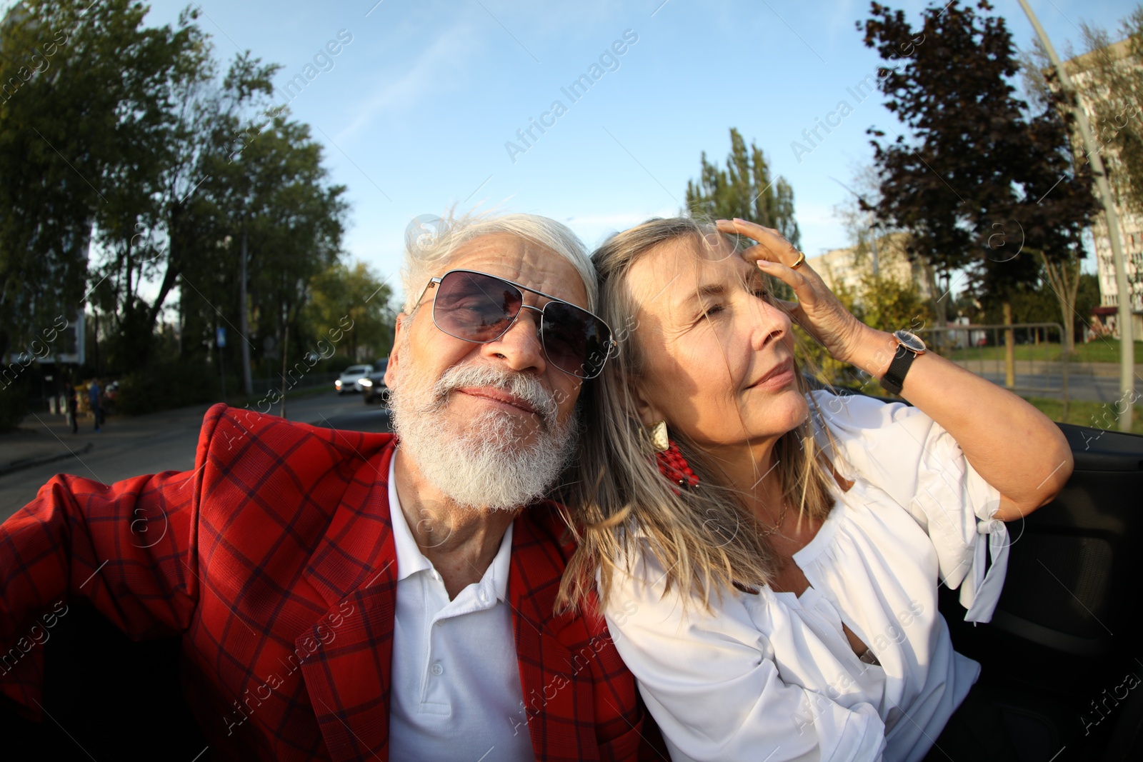 Photo of Senior couple enjoying cabriolet ride in city, wide angle lens