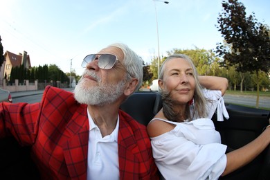 Photo of Senior couple enjoying cabriolet ride in city, wide angle lens