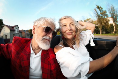 Photo of Senior couple enjoying cabriolet ride in city, wide angle lens