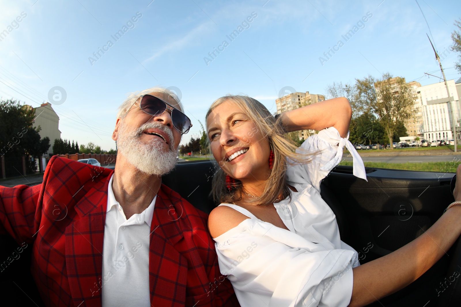 Photo of Senior couple enjoying cabriolet ride in city, wide angle lens