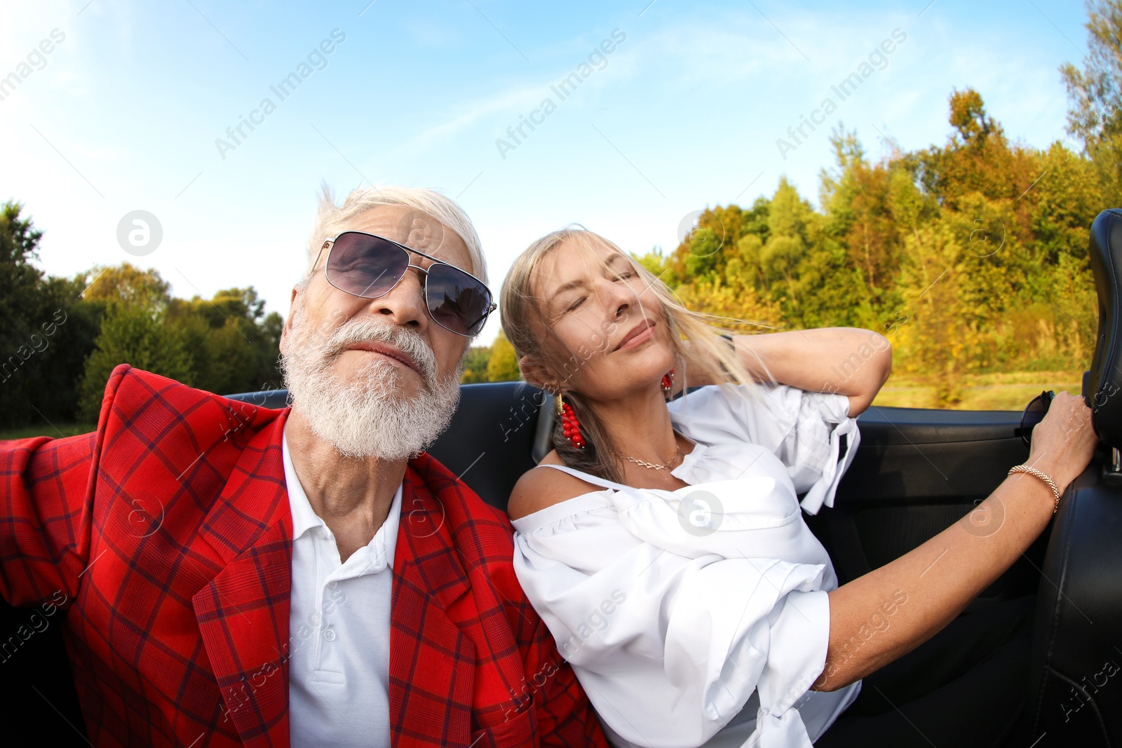 Photo of Senior couple enjoying cabriolet ride outdoors, wide angle lens