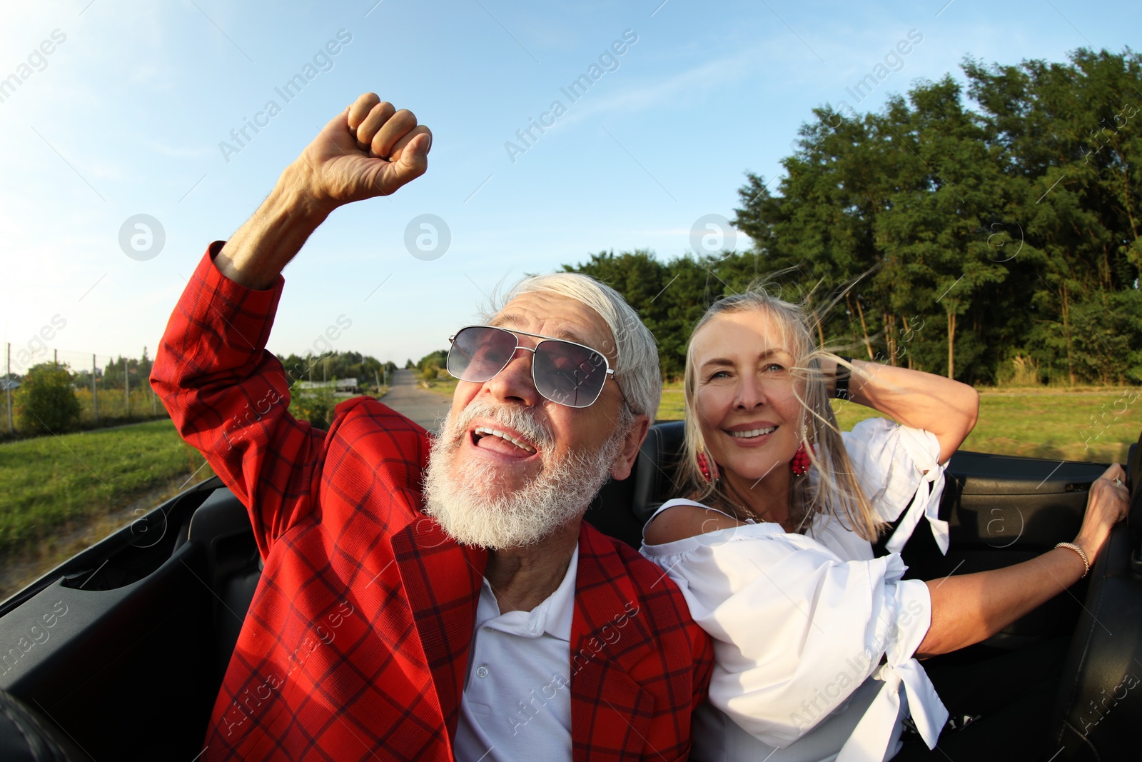 Photo of Senior couple enjoying cabriolet ride outdoors, wide angle lens