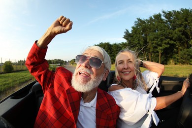 Photo of Senior couple enjoying cabriolet ride outdoors, wide angle lens