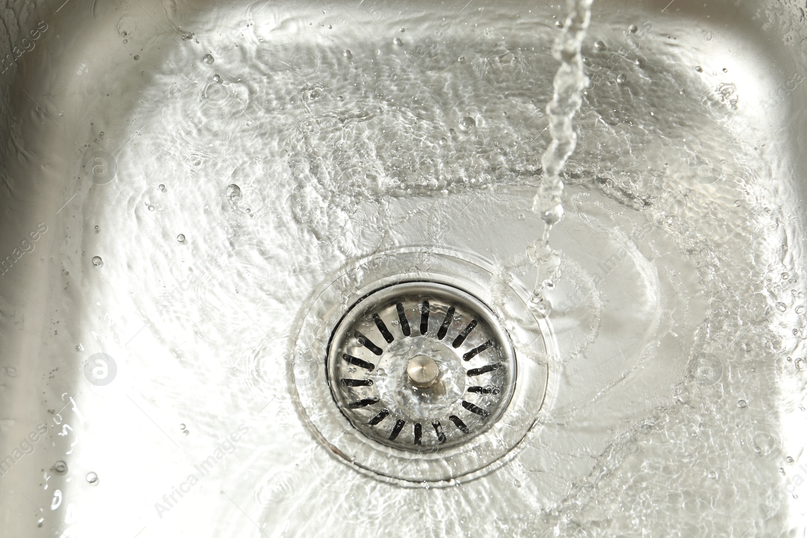 Photo of Water going down sink drain, closeup view