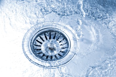 Photo of Water going down sink drain, closeup view