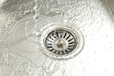Photo of Water going down sink drain, closeup view