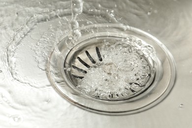 Photo of Water going down sink drain, closeup view