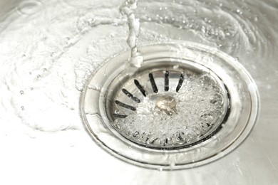 Photo of Water going down sink drain, closeup view