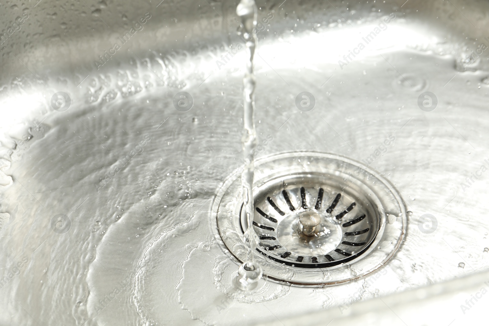 Photo of Water going down sink drain, closeup view