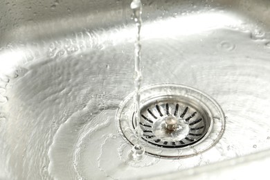 Photo of Water going down sink drain, closeup view