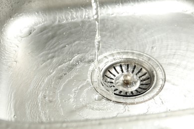 Photo of Water going down sink drain, closeup view