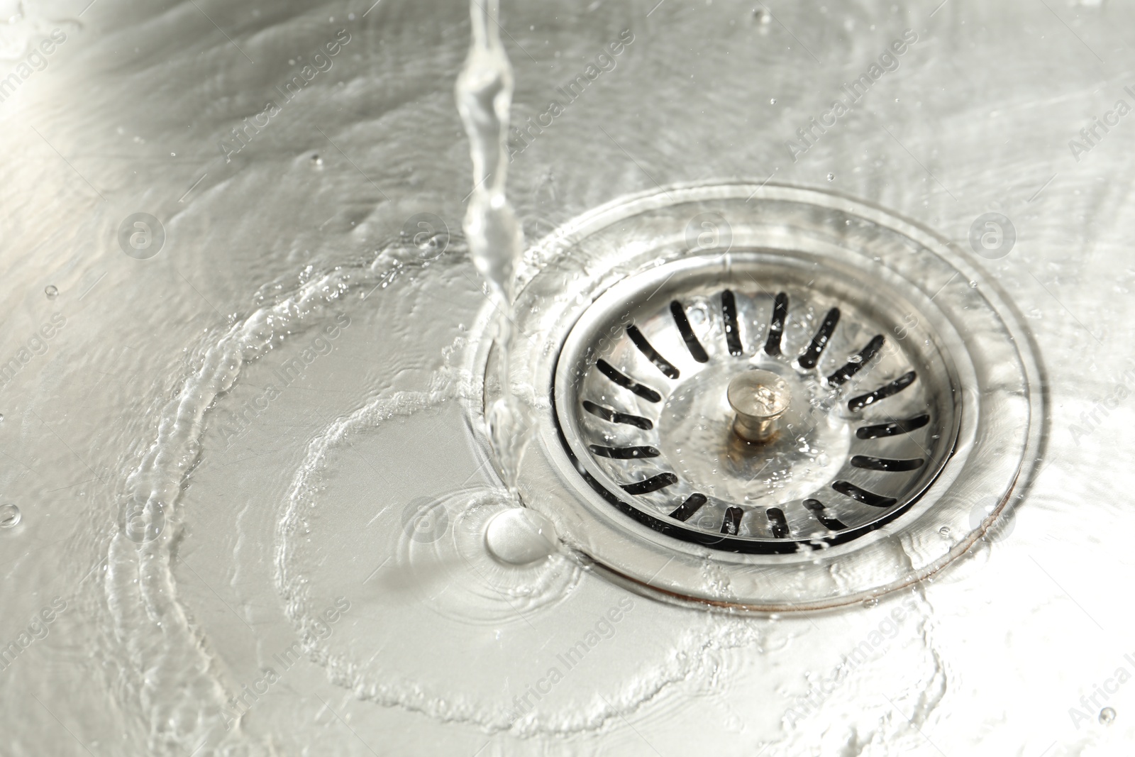 Photo of Water going down sink drain, closeup view