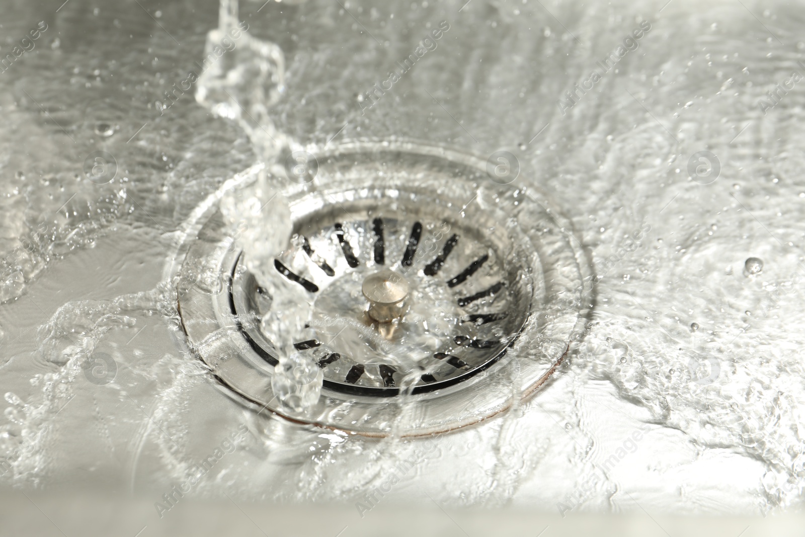 Photo of Water going down sink drain, closeup view