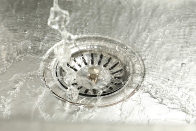 Photo of Water going down sink drain, closeup view