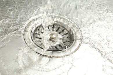Photo of Water going down sink drain, closeup view