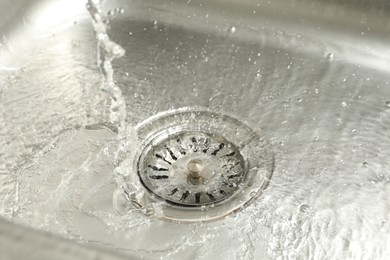 Photo of Water going down sink drain, closeup view