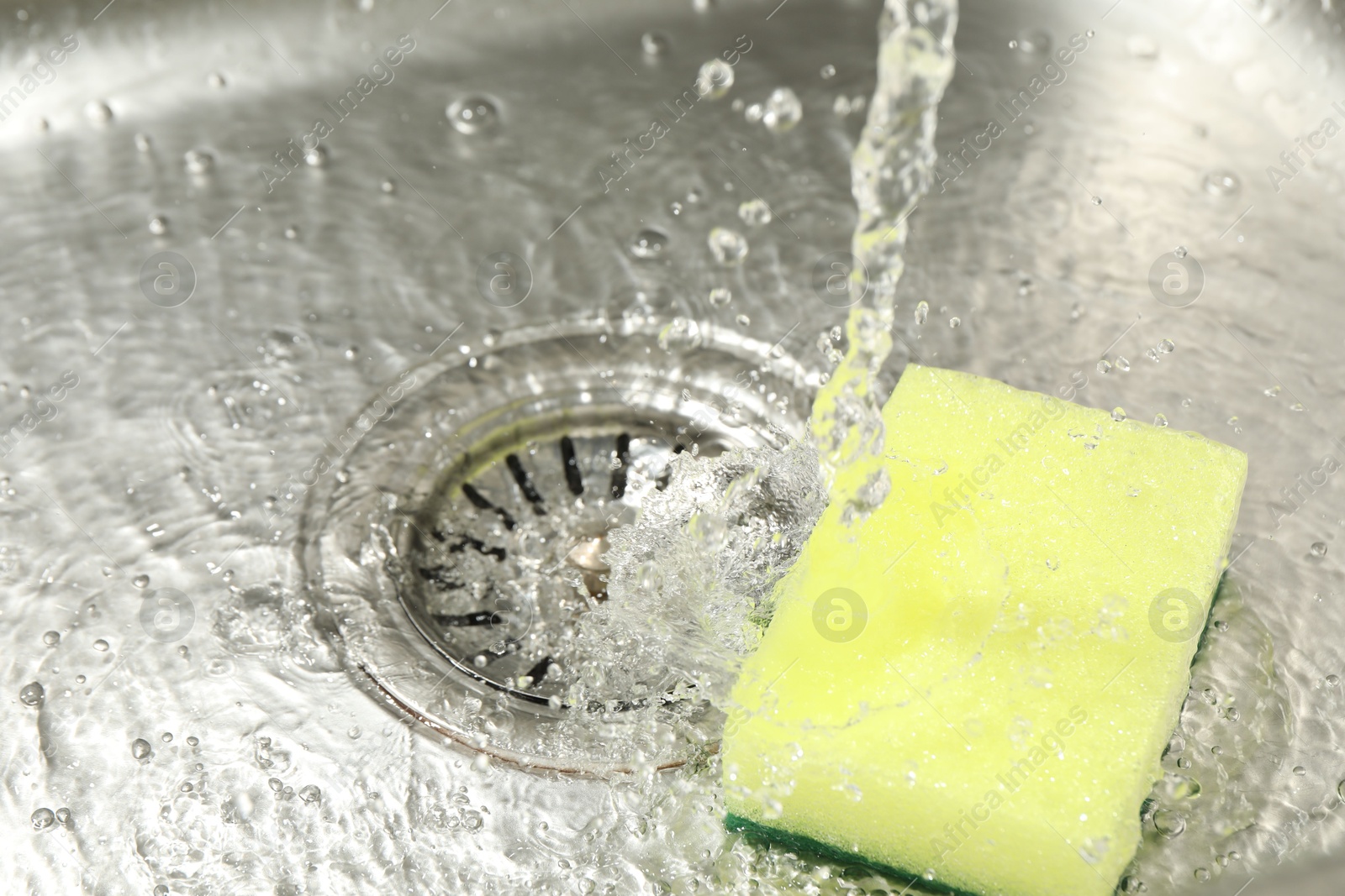 Water going down drain and sponge in sink, closeup Photo of Water going down drain and sponge in sink, closeup