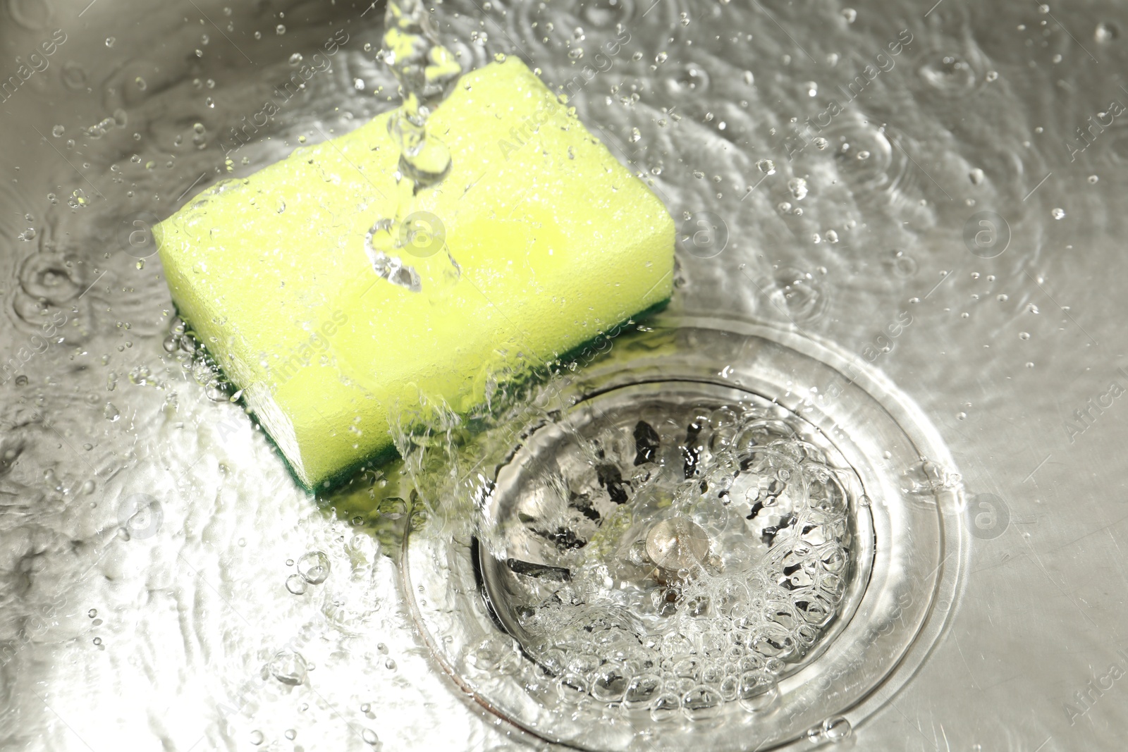 Water going down drain and sponge in sink, closeup Photo of Water going down drain and sponge in sink, closeup