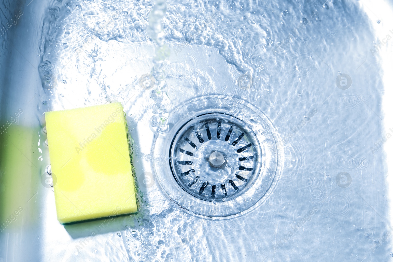 Water going down drain and sponge in sink, top view Photo of Water going down drain and sponge in sink, top view