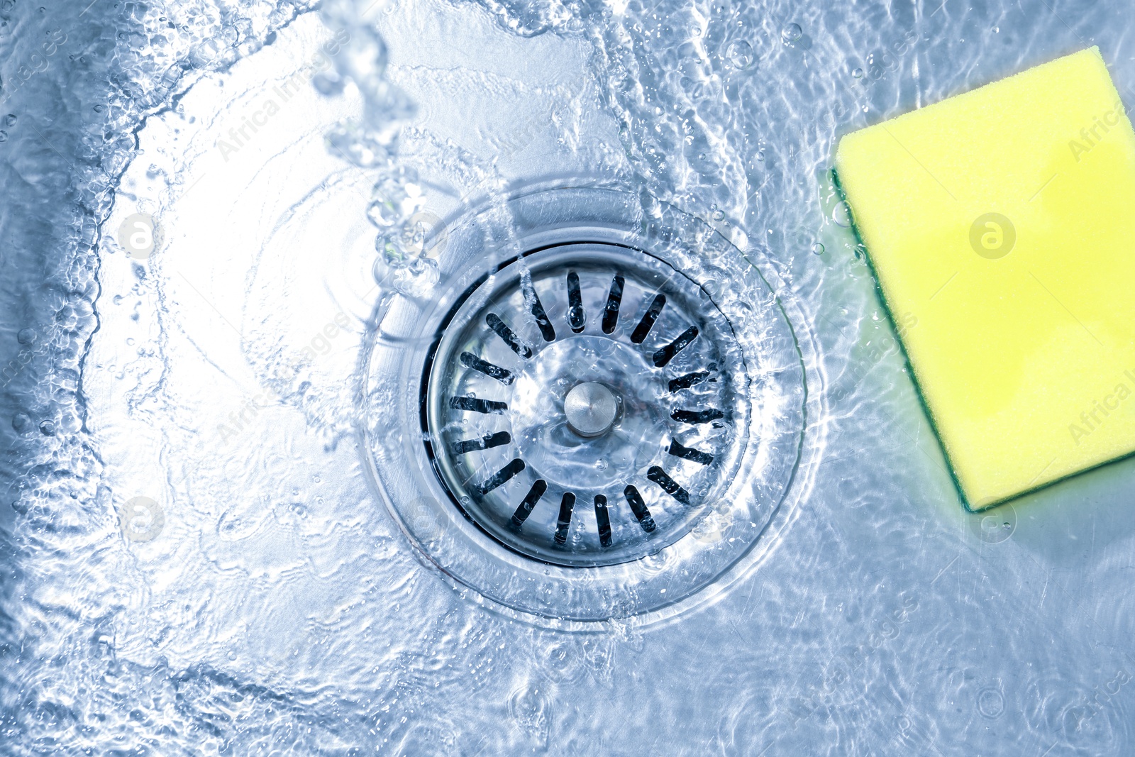 Water going down drain and sponge in sink, top view Photo of Water going down drain and sponge in sink, top view