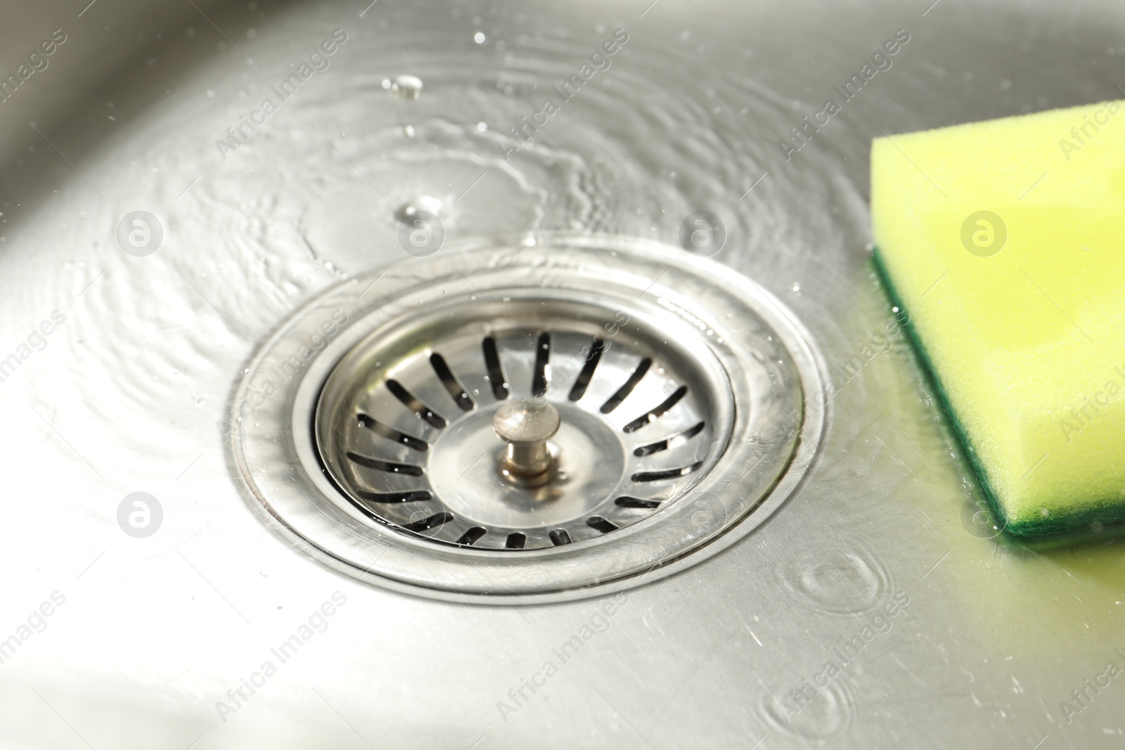 Water going down drain and sponge in sink, closeup Photo of Water going down drain and sponge in sink, closeup