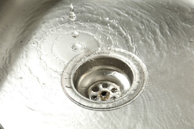 Photo of Water going down sink drain, closeup view