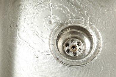 Photo of Water going down sink drain, closeup view