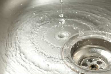 Photo of Water going down sink drain, closeup view