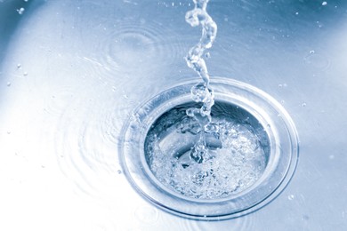 Photo of Water going down sink drain, closeup view