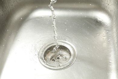 Photo of Water going down sink drain, closeup view