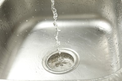 Photo of Water going down sink drain, closeup view