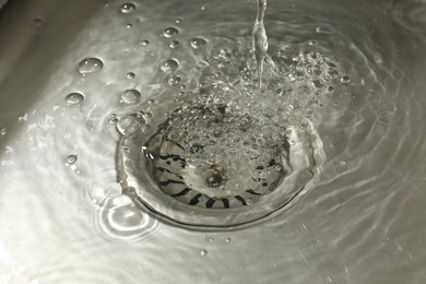 Photo of Water going down sink drain, closeup view