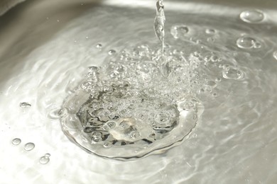 Photo of Water going down sink drain, closeup view