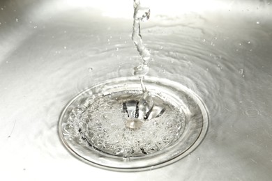 Photo of Water going down sink drain, closeup view