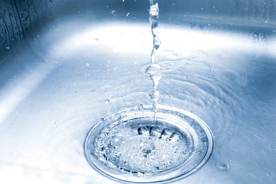 Photo of Water going down sink drain, closeup view
