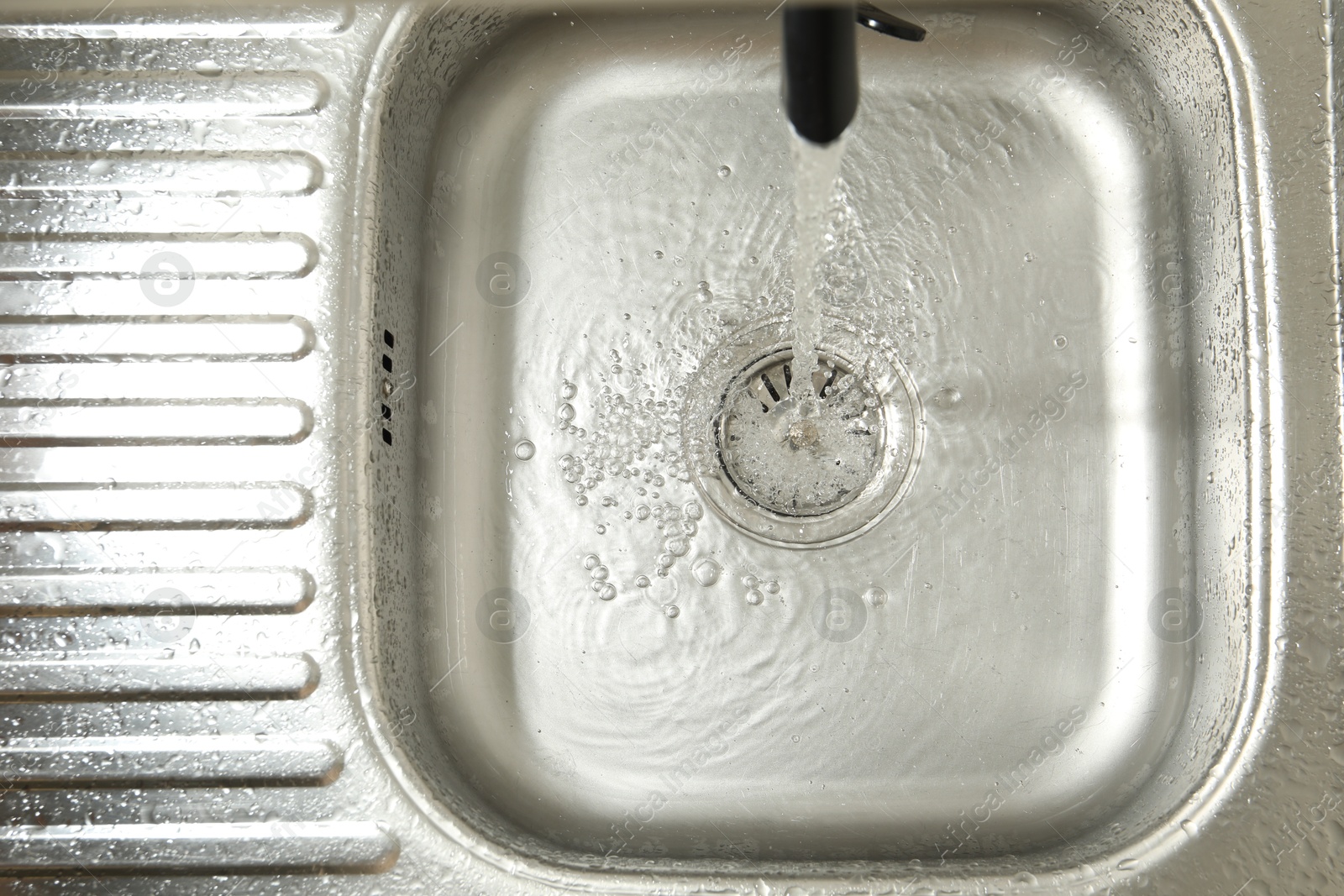 Water flowing from tap into sink, top view Photo of Water flowing from tap into sink, top view