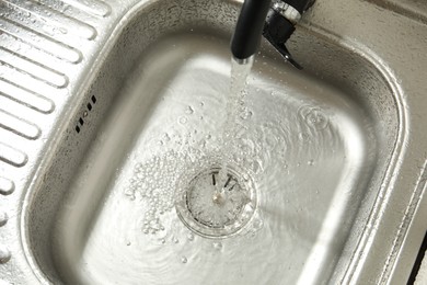 Photo of Water flowing from tap into sink, above view