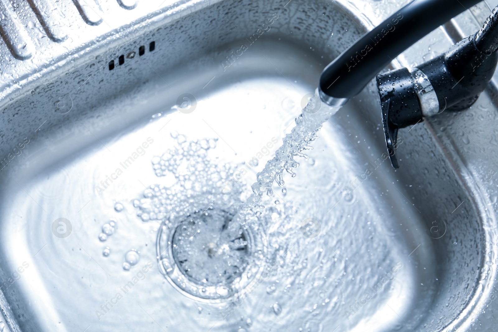 Water flowing from tap into sink, above view Photo of Water flowing from tap into sink, above view