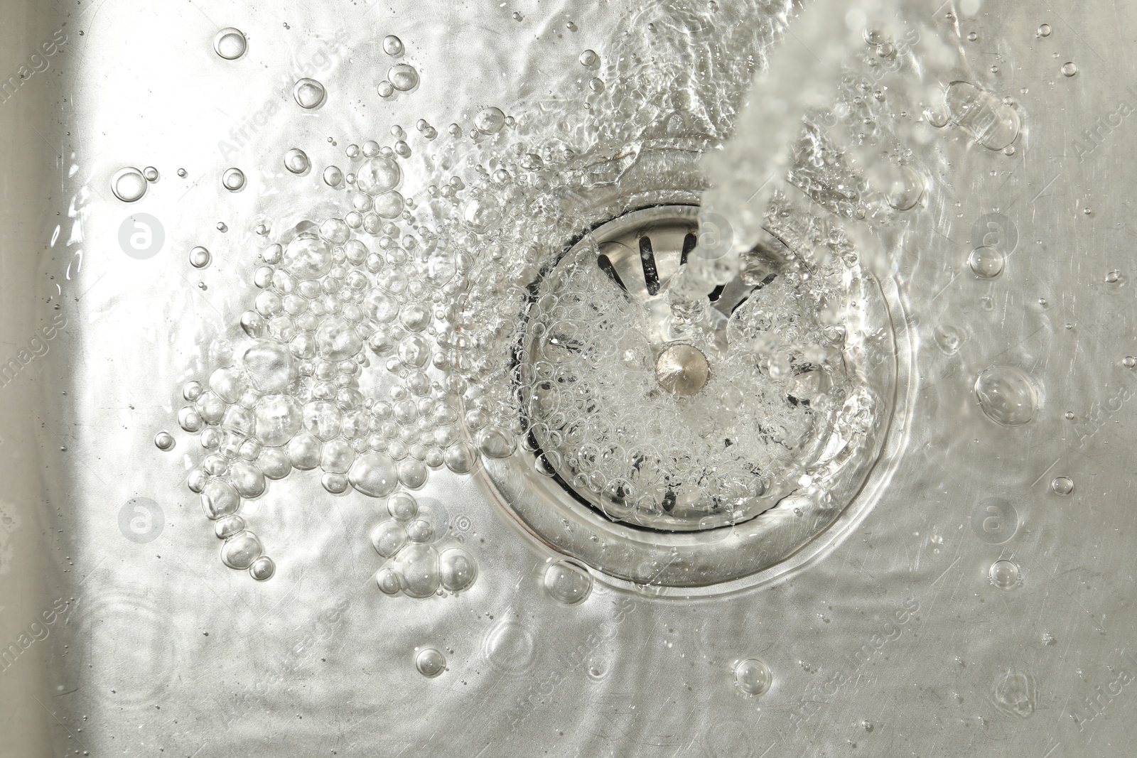 Stream of water going into sink drain, closeup Photo of Stream of water going into sink drain, closeup