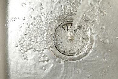 Photo of Stream of water going into sink drain, closeup