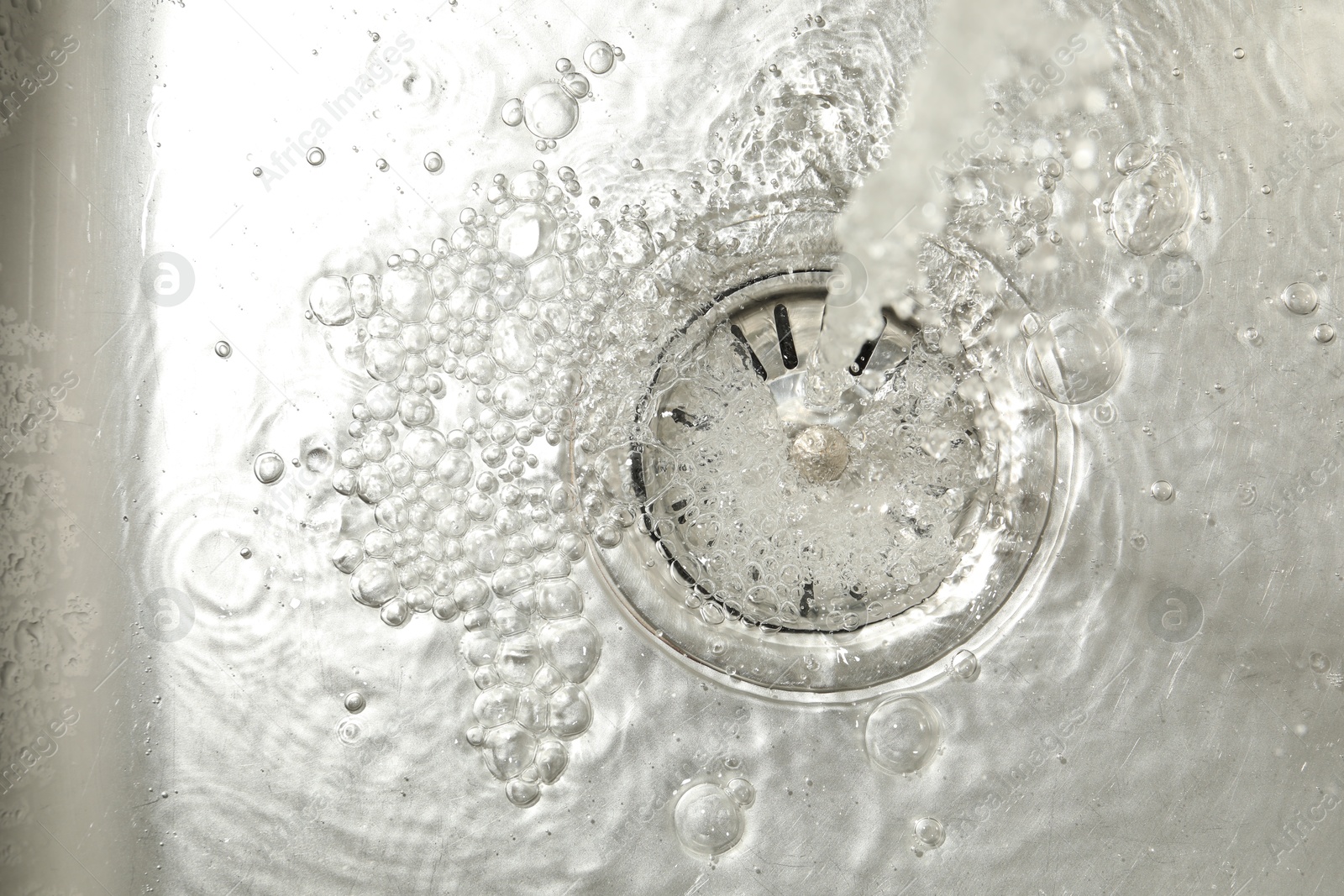Stream of water going into sink drain, closeup Photo of Stream of water going into sink drain, closeup