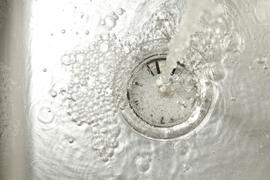 Photo of Stream of water going into sink drain, closeup