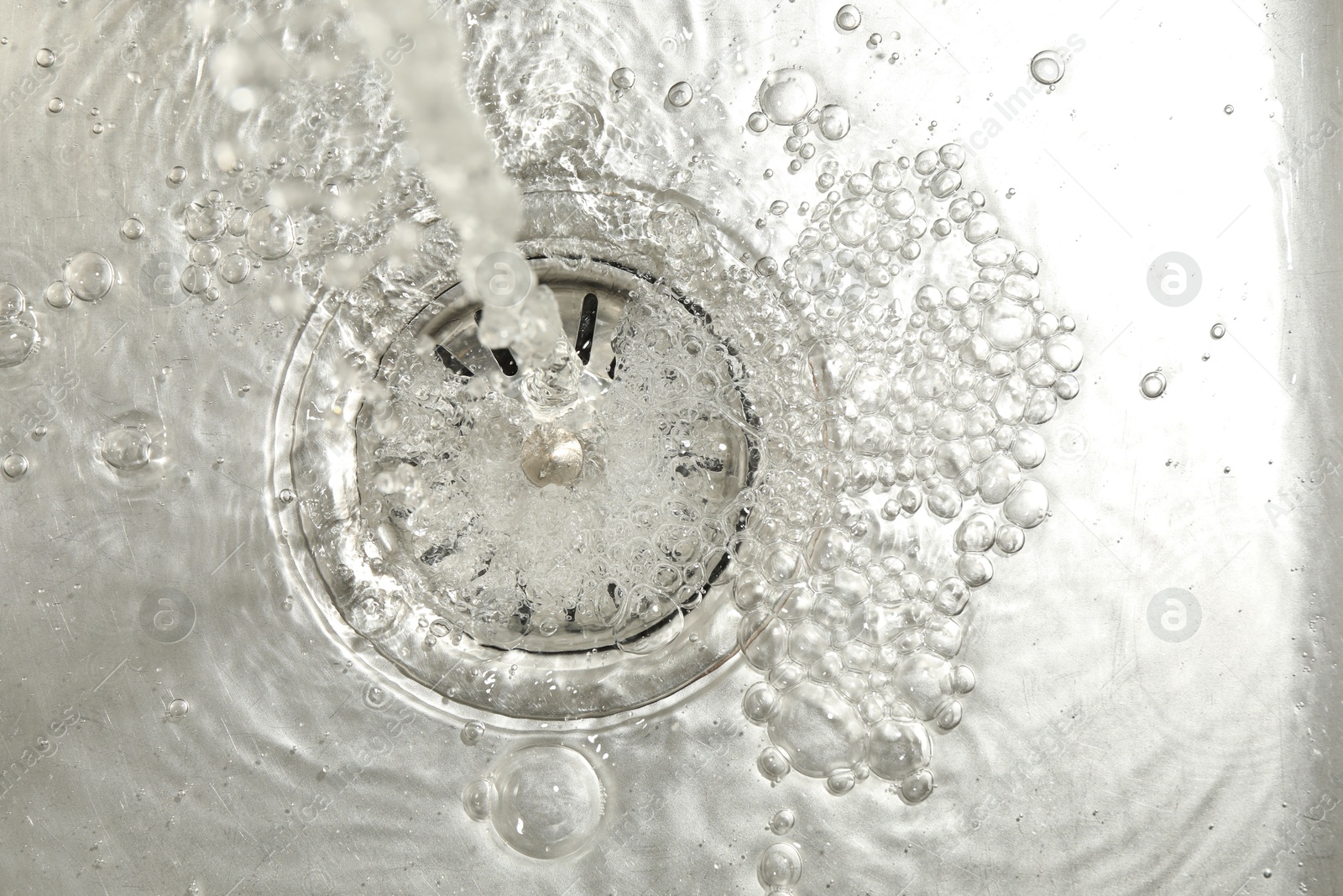 Stream of water going into sink drain, closeup Photo of Stream of water going into sink drain, closeup