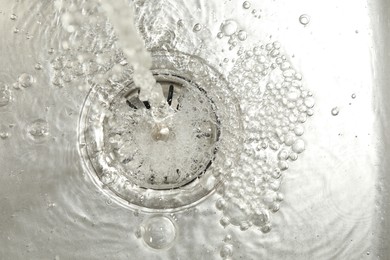 Photo of Stream of water going into sink drain, closeup