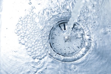 Photo of Stream of water going into sink drain, closeup