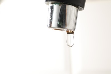 Photo of Water dripping down from faucet on white background, closeup. Space for text